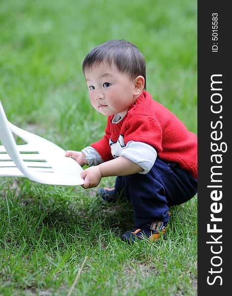 Little boy in red is trying to move a chair. Little boy in red is trying to move a chair.