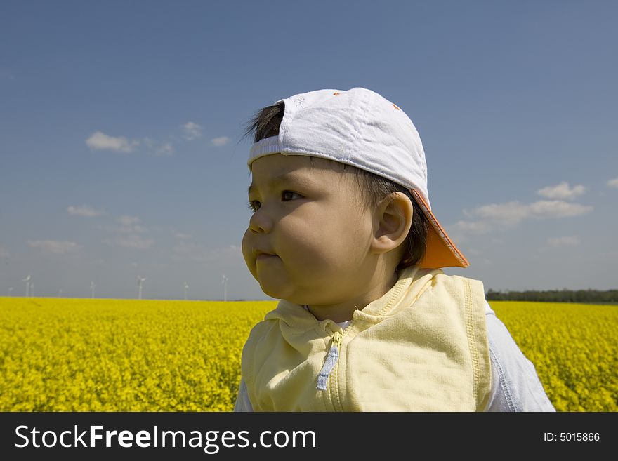 Baby in the rape field with beautiful spring weather