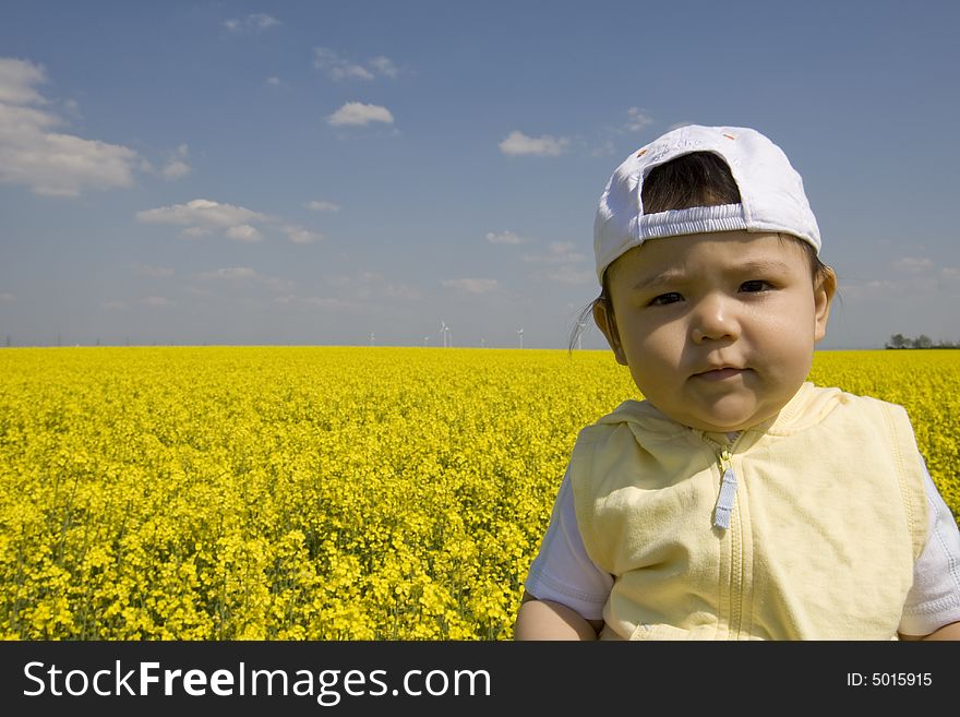 Baby in the rape field with beautiful spring weather