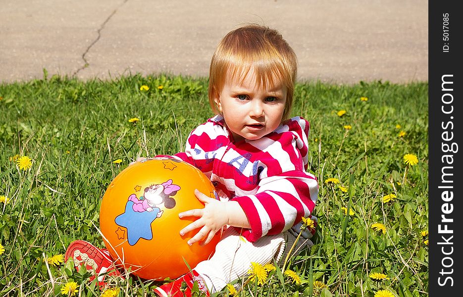 The little girl with ball on a grass