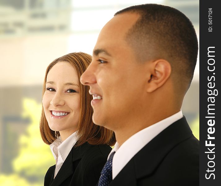 Shot of two business people standing side by side. the woman look to the camera and smile while the man look to the side. Shot of two business people standing side by side. the woman look to the camera and smile while the man look to the side