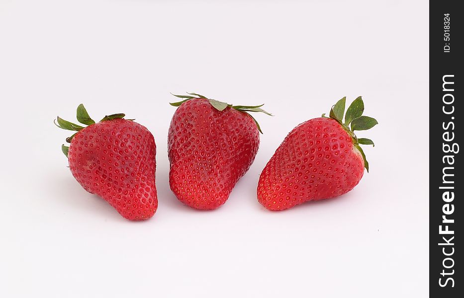 Three red, fresh and tasty strawberries on white background