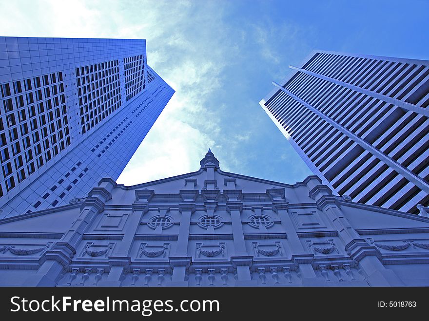 Futuristic skyscrapers tower over a small unique building. Futuristic skyscrapers tower over a small unique building.