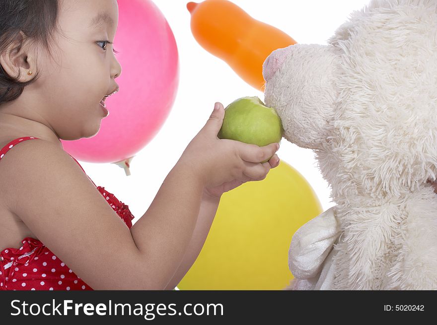 Toddler girl trying to feed teddy bear