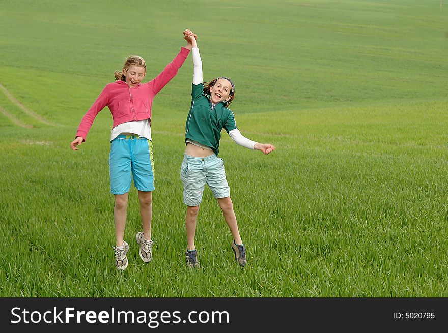 Girls jumping in the air in a green field
