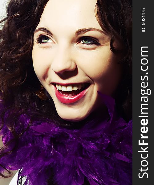 A portrait about an attractive happy lady with white skin, long brown wavy hair and a scarf made with vivid purple feathers. A portrait about an attractive happy lady with white skin, long brown wavy hair and a scarf made with vivid purple feathers