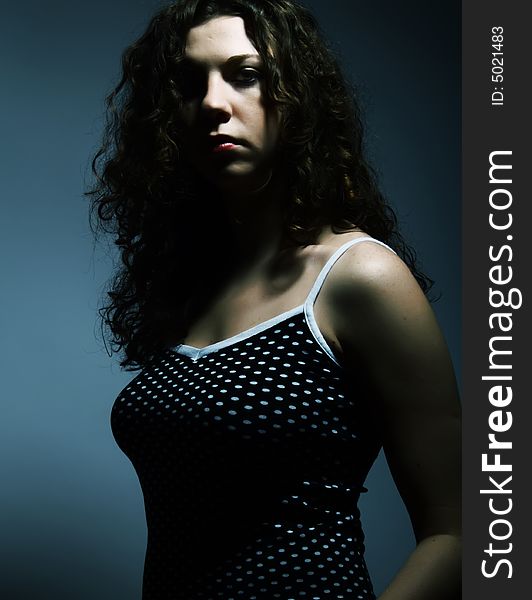 A dark low-key portrait about a pretty lady with white skin and long brown wavy hair whose look is strongly attractive and she wears a nice black dress with white dots. A dark low-key portrait about a pretty lady with white skin and long brown wavy hair whose look is strongly attractive and she wears a nice black dress with white dots