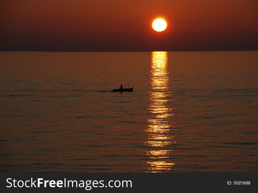 Man on a rowing boat. Sunset. Liguria Region, Italy