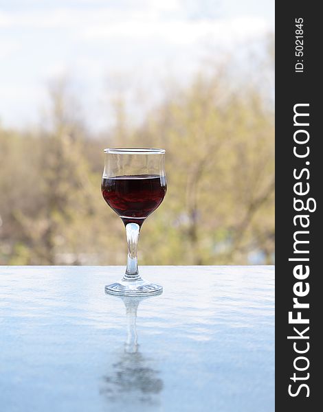 Nice goblet of red wine on background with blue sky and clouds. Nice goblet of red wine on background with blue sky and clouds