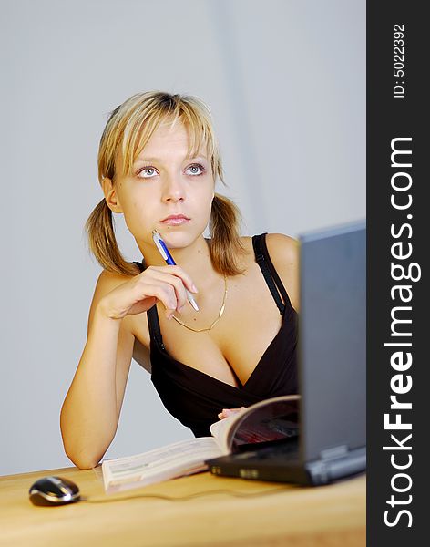 A young blonde girl working with a notebook in an office