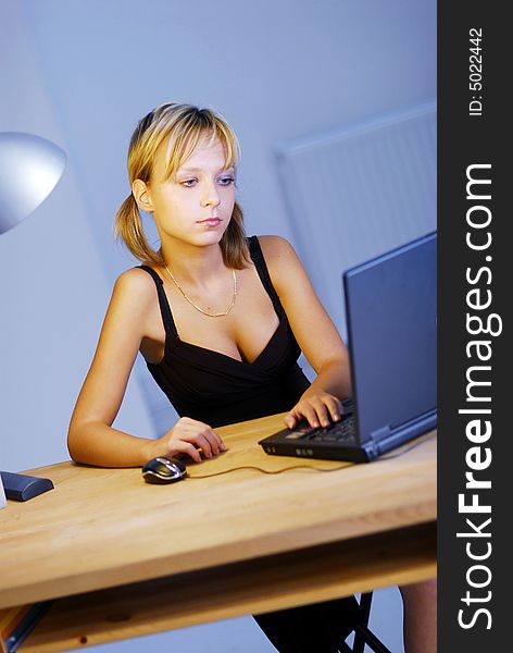 A young blonde girl working with a notebook in an office