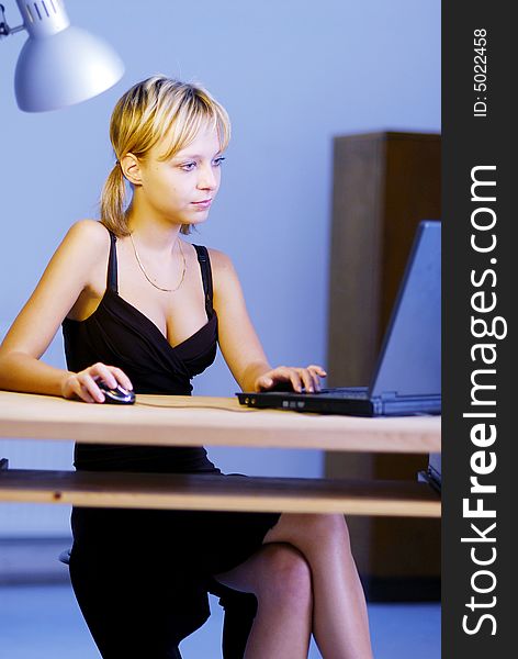 A young blonde girl working with a notebook in an office