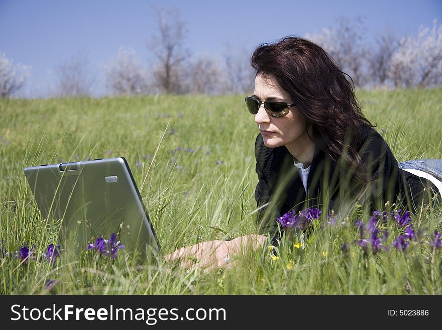 Woman laying down on grass with laptop. Woman laying down on grass with laptop