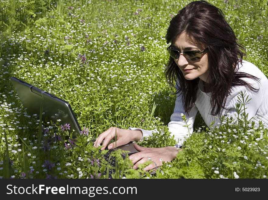 Woman laying down on grass with laptop. Woman laying down on grass with laptop