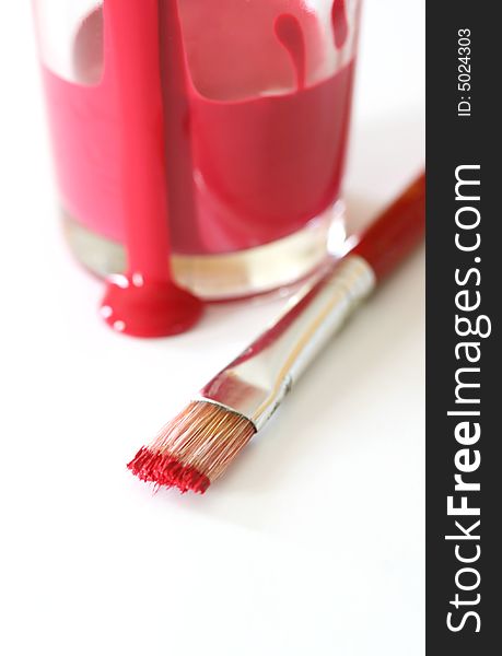 A cup of red paint with a paintbrush. A cup of red paint with a paintbrush
