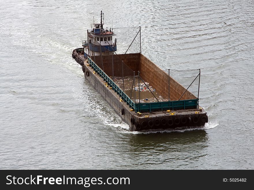 Empty boat for transporting garbage cruising in a river, used for waste management. Empty boat for transporting garbage cruising in a river, used for waste management