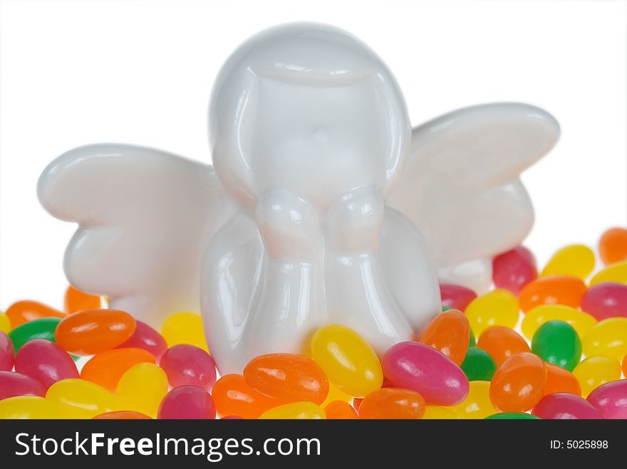 Close up to ceramic white angel placed over colorful Easter Candy. Close up to ceramic white angel placed over colorful Easter Candy