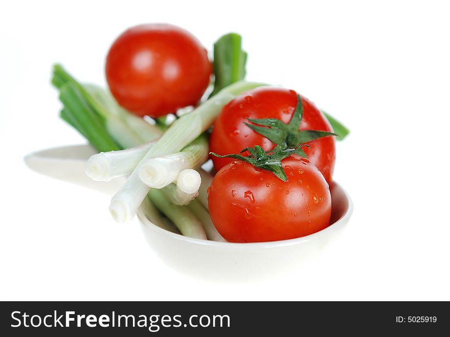 Fresh green onions and tomatoes are placed in ceramic bowl on white background. Fresh green onions and tomatoes are placed in ceramic bowl on white background