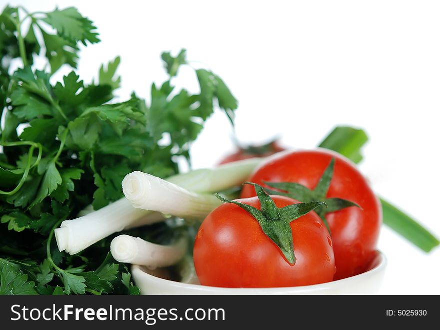 Close up to Fresh green onions, parsley and tomatoes are placed in ceramic bowl on white background. Close up to Fresh green onions, parsley and tomatoes are placed in ceramic bowl on white background