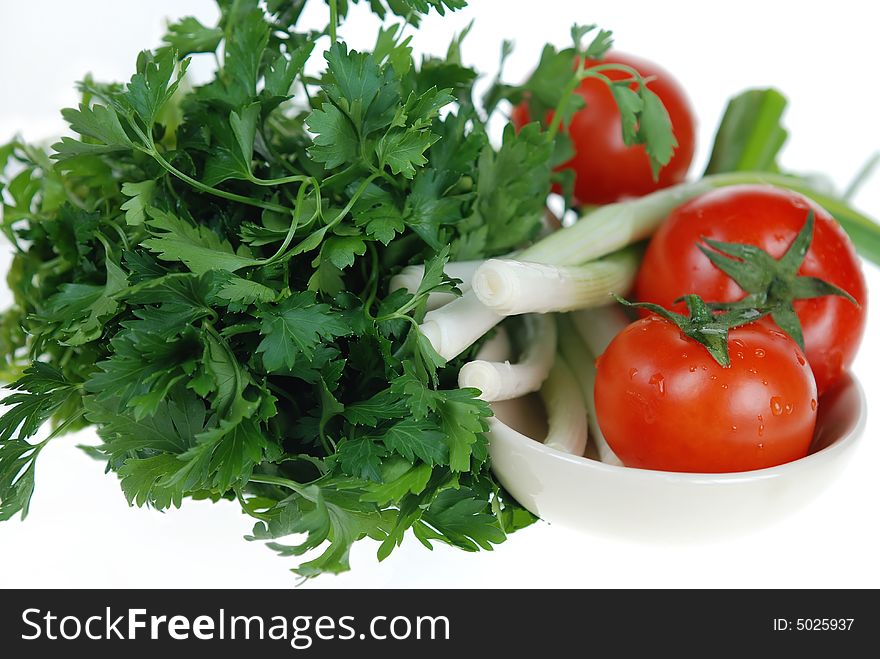 Fresh green onions, parsley and tomatoes are placed in ceramic bowl on white background. Fresh green onions, parsley and tomatoes are placed in ceramic bowl on white background