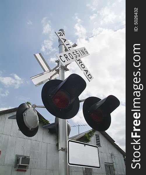 Railroad crossing signal lights with a blue sky and white clouds above. Railroad crossing signal lights with a blue sky and white clouds above.