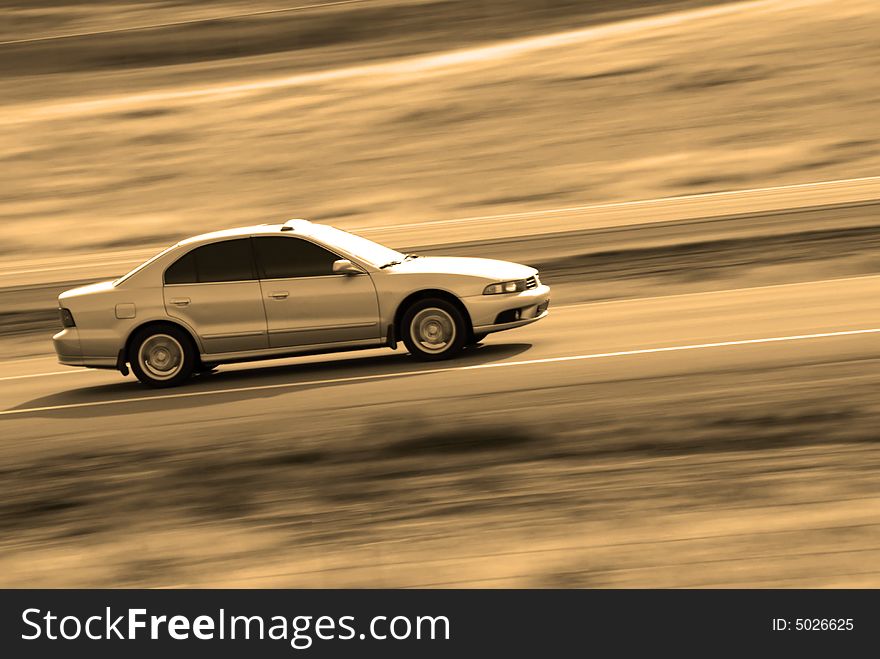 Four door sedan driving along road with blurred background