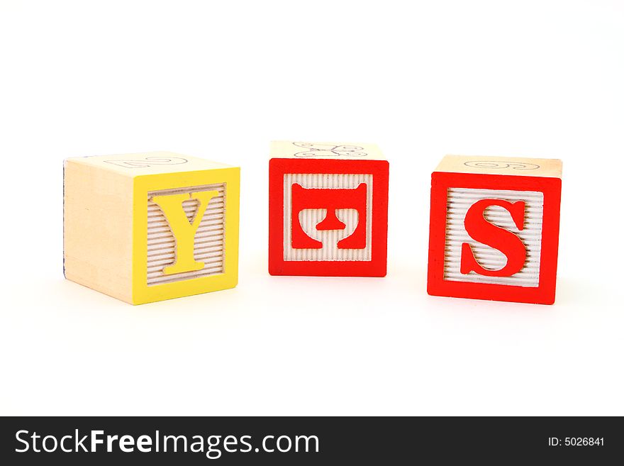 Word yes formed by letter wood blocks over a white surface
