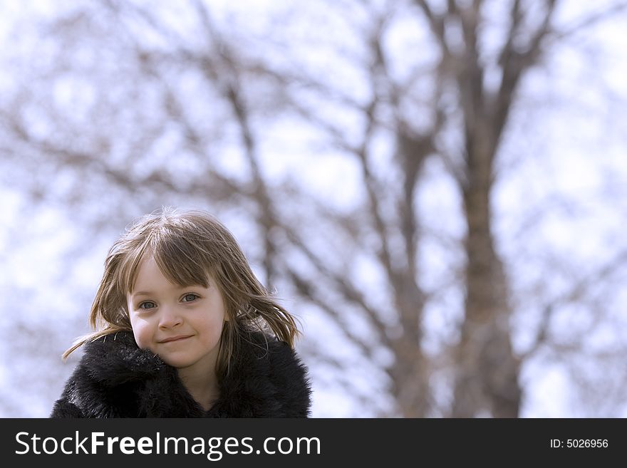 A young, pretty girl outside at the park with a tree in the background. A young, pretty girl outside at the park with a tree in the background.