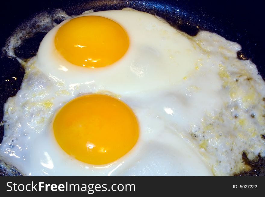 Two eggs frying in open pan. Two eggs frying in open pan