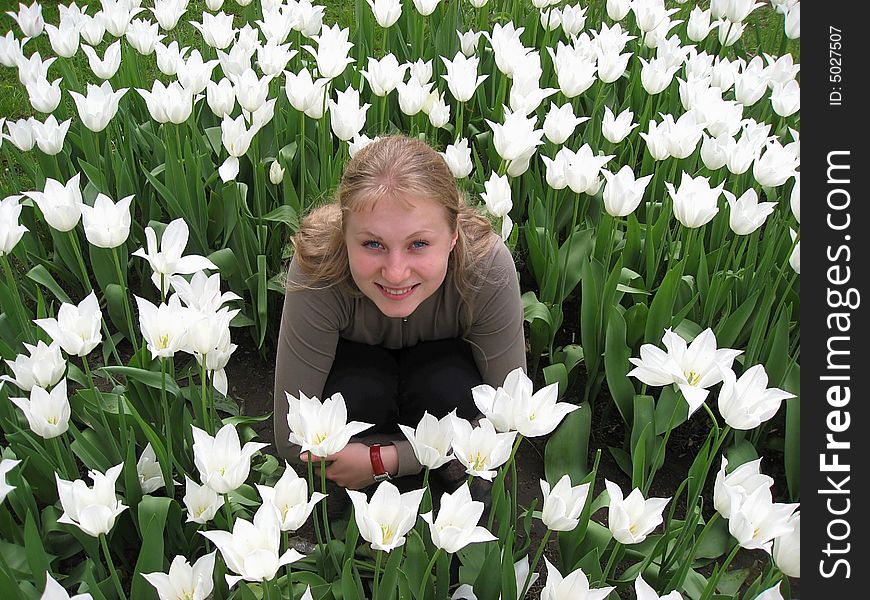 Beautiful girl sitting in the meadow among white tulips. Beautiful girl sitting in the meadow among white tulips