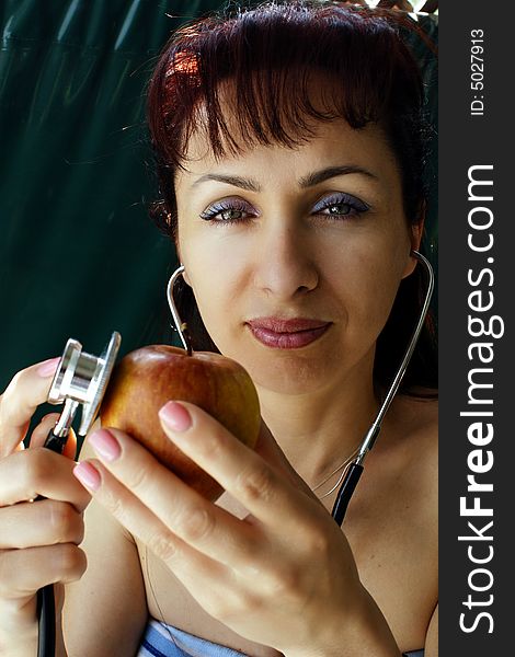 Young woman examining apple with stethoscope. Young woman examining apple with stethoscope