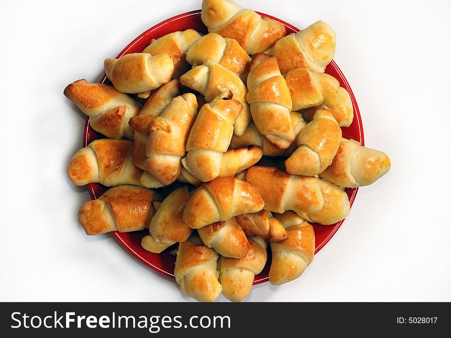 Appetizing rolled hand-made pastry on red plate isolated over white. Appetizing rolled hand-made pastry on red plate isolated over white