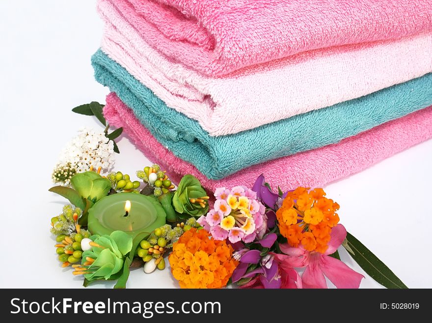 Stack of clean colorful towels with candle and flowers.