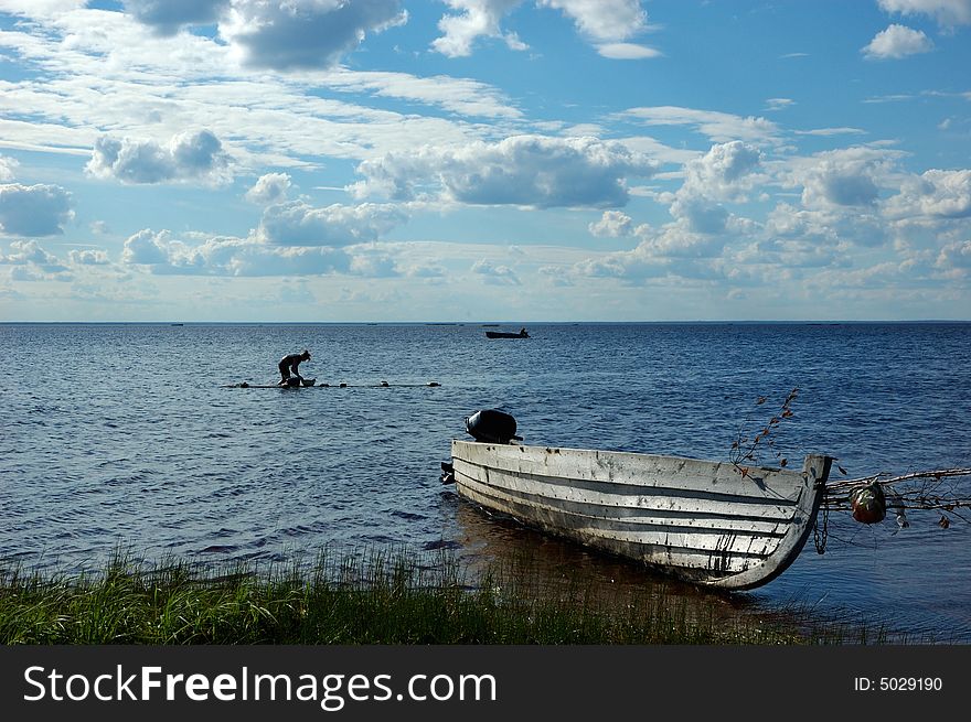 Lake view with old wooden fishing motor boat and washing woman. Lake view with old wooden fishing motor boat and washing woman