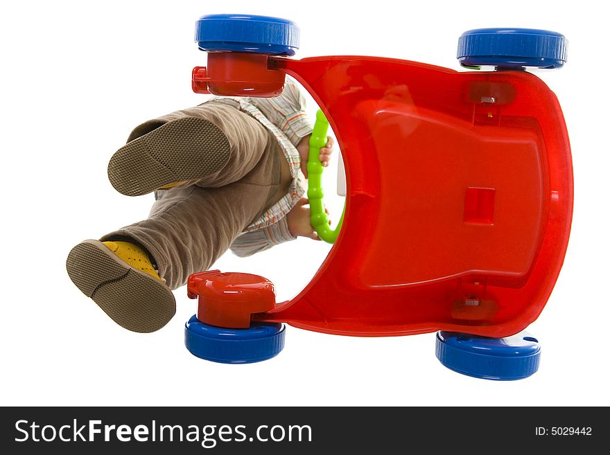 Baby pushing red baby cart. Isolated on white background. Unusual angle view - directly below. Baby pushing red baby cart. Isolated on white background. Unusual angle view - directly below.