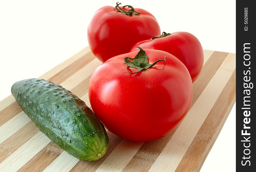 Vegetables (tomatoes and cucumber) on bamboo cutting board. Vegetables (tomatoes and cucumber) on bamboo cutting board.