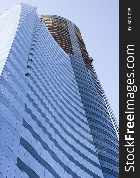 A modern curving blue glass office tower under construction. A modern curving blue glass office tower under construction