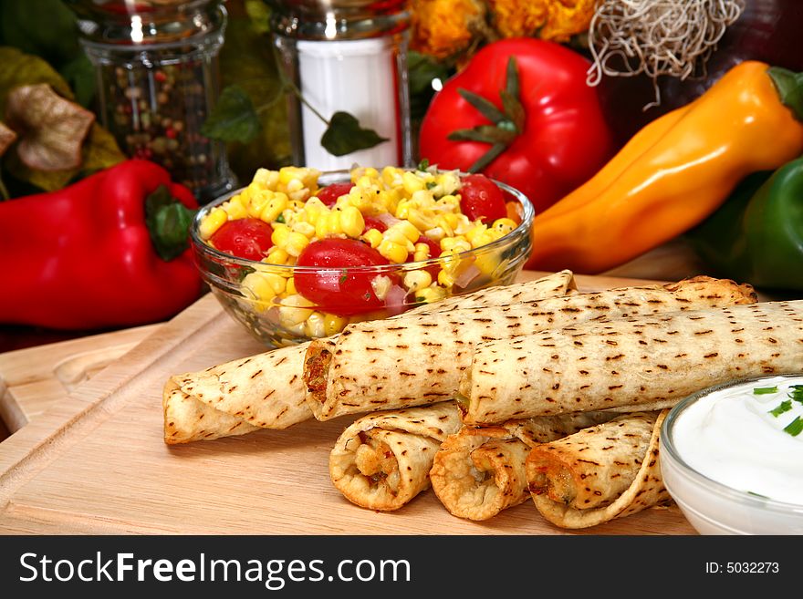 Stack of chicken taquitos with hot sauce and sour cream in kitchen or restaurant