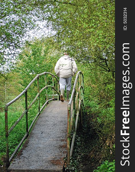 Shot of a man walking across a forest bridge. Shot of a man walking across a forest bridge