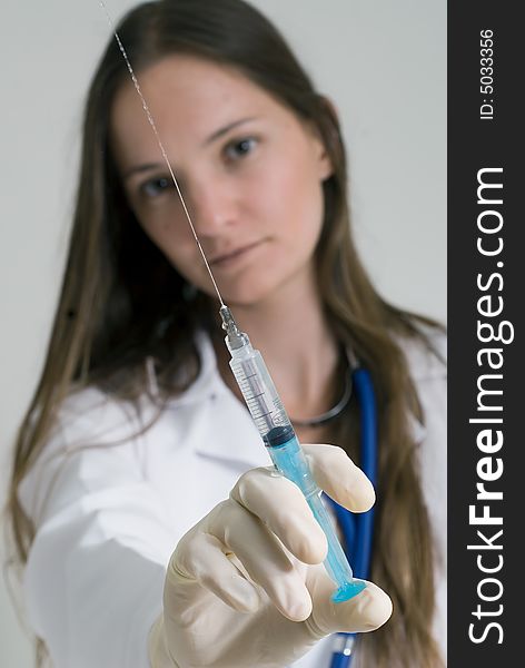 Young female doctor holding syringe in her outstretched arm. Isolated. Young female doctor holding syringe in her outstretched arm. Isolated.