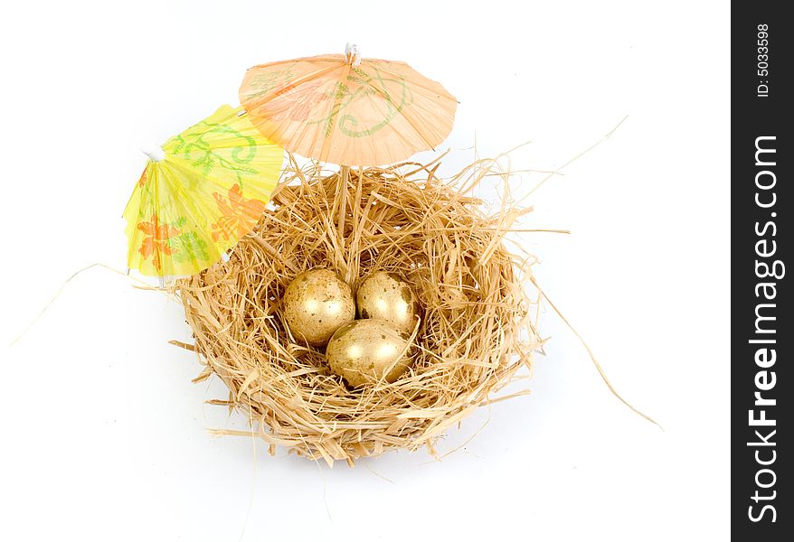 Bird nest with three golden eggs under colorful cocktail umbrellas. Bird nest with three golden eggs under colorful cocktail umbrellas