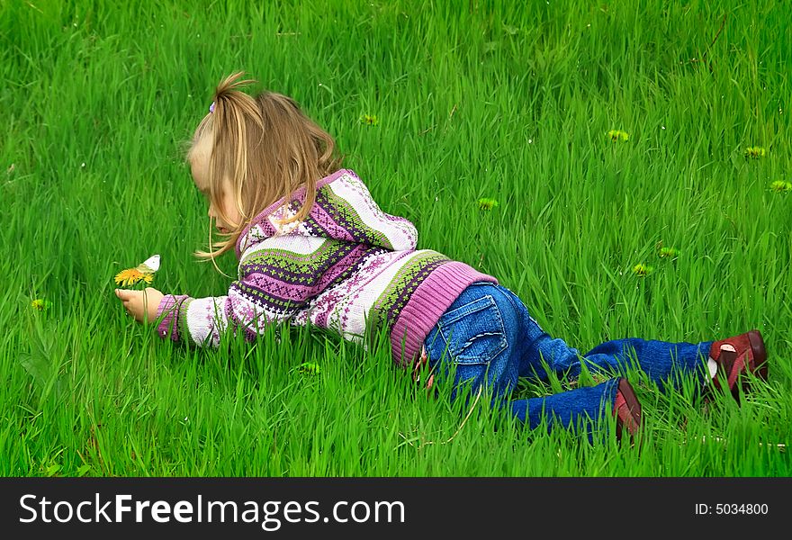 Little girl walks in the spring on a young grass in park
