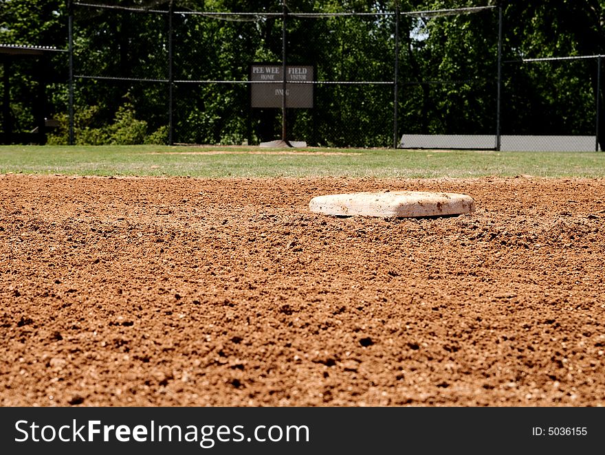 A baseball base on a little league field in focus. A baseball base on a little league field in focus.