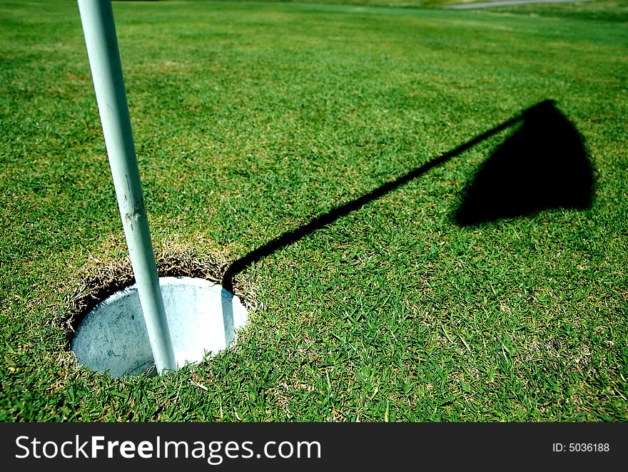 A golf hole on a green of a golfcourse with focus on the flag. A golf hole on a green of a golfcourse with focus on the flag.