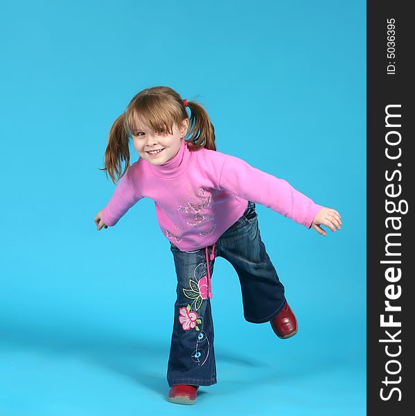 The child stand on one leg on a blue background. The child stand on one leg on a blue background