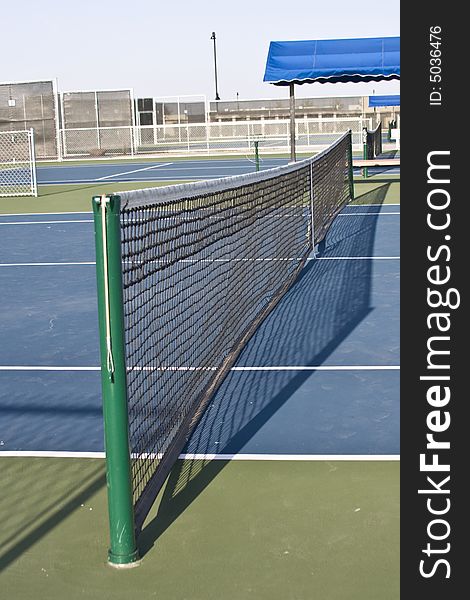 Tennis court net viewed from one end with bench. Tennis court net viewed from one end with bench