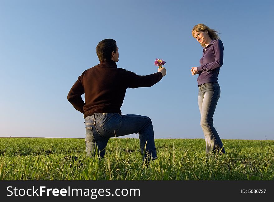 Guy stand on a knee and gives a bouquet to the girl. Guy stand on a knee and gives a bouquet to the girl