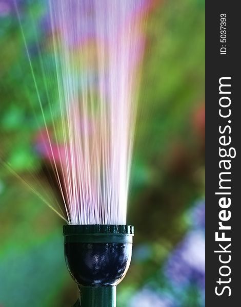 Water sprinkler with gush of water against colorful background