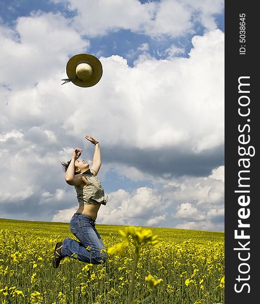 Young attractive girl jumping in field and throwing straw hat. Young attractive girl jumping in field and throwing straw hat