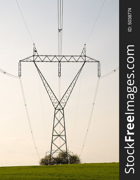 Silhouette of the electricity pylon with cables and the blue sky